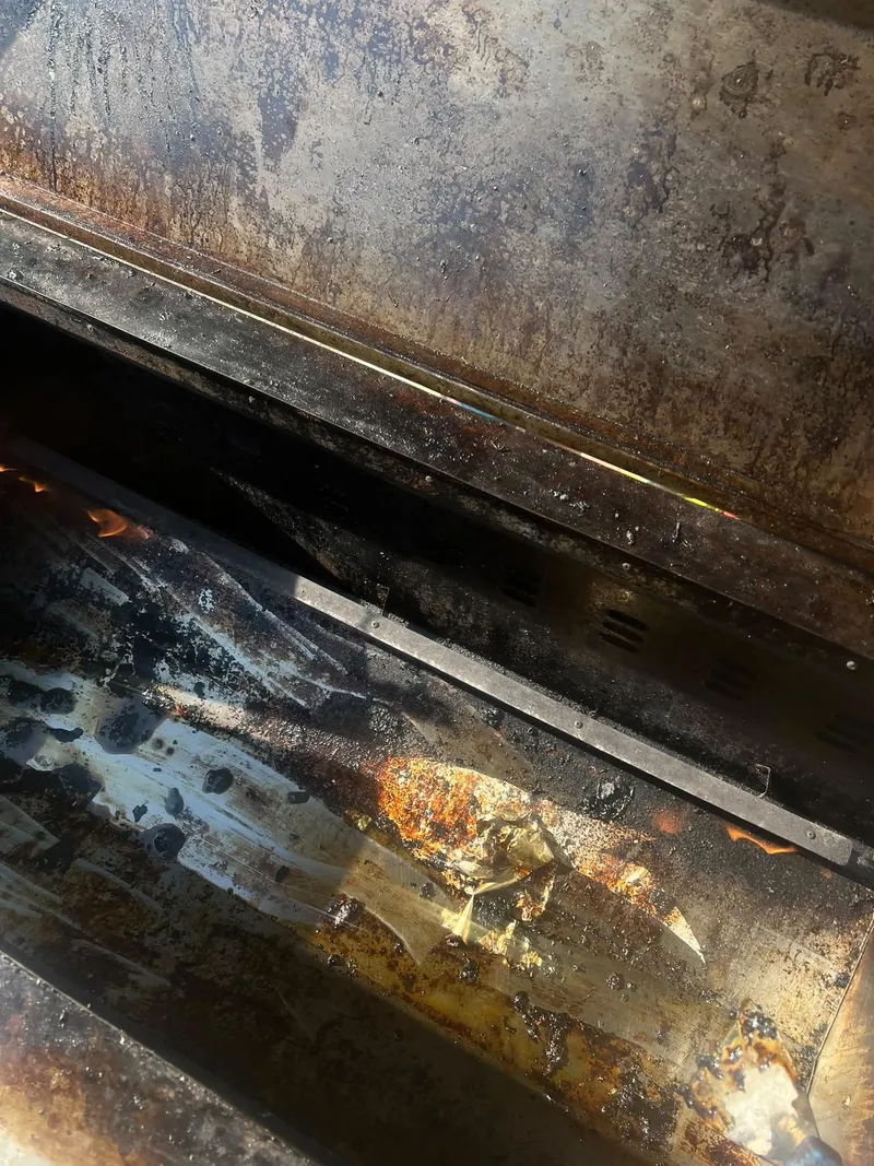 Close-up of burnt grease and fat inside a hog roast machine