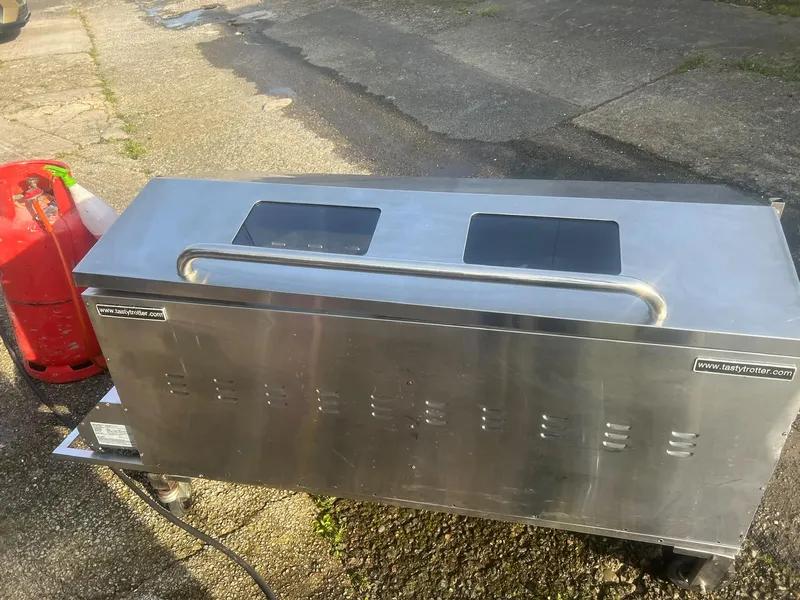 Stainless steel hog roast machine after cleaning, shining beside its gas bottle